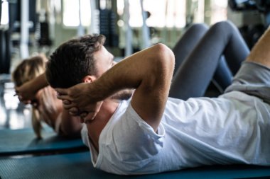 Erkek ve kadın spor salonunda hasırda oturur sağlıklı yaşam tarzını geliştirirler.