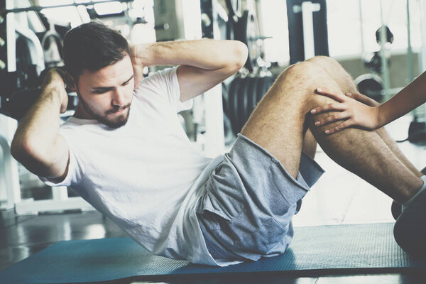 Sport man sit uplying on yoga mat exercise in gym help with woman hand