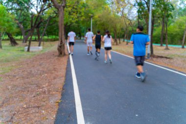 Açık yeşil ağaç parkında koşan bulanık insanlar.