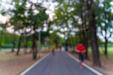 Açık yeşil ağaç parkında koşan bulanık insanlar.