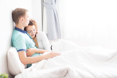 Aşk çifti sabah beyaz yatakta uzanıyor. Mutlular ve birbirlerine sarılıyorlar. Sevginin rahatlığı.