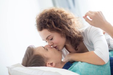 Aşk çifti sabah beyaz yatakta uzanıyor. Mutlular ve birbirlerine sarılıyorlar. Sevginin rahatlığı.