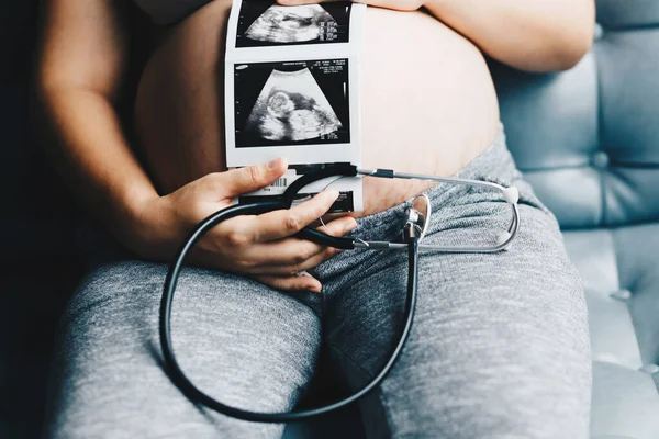 Mujer Embarazada Escuchar Bebé Con Estetoscopio Sentado Sofá Habitación Acogedora — Foto de Stock