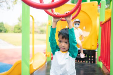 Mutlu Asyalı çocuk oyun parkına tırmanıyor. Açık hava aktivitesi.