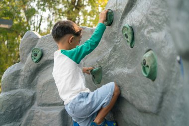 Mutlu Asyalı çocuk oyun parkına tırmanıyor. Açık hava aktivitesi.