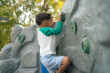 Mutlu Asyalı çocuk oyun parkına tırmanıyor. Açık hava aktivitesi.