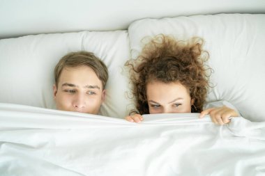 Beyaz yatakta uyuyan sevimli çift. Sabah sahnesi. Mutlu balayı.