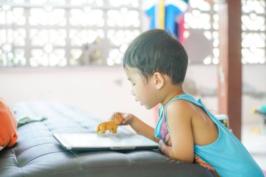 Tabletle oynayan sevimli küçük çocuk evde çizgi film izliyor.