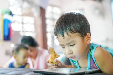 Tablet oynayan sevimli küçük çocuk evde çizgi film izliyor.