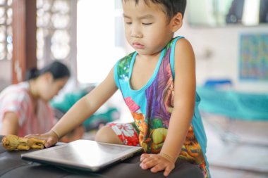 Tablet oynayan sevimli küçük çocuk evde çizgi film izliyor.