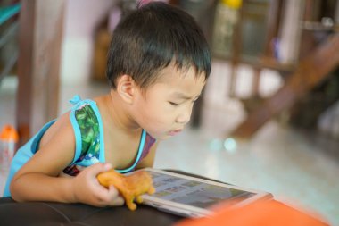 Tablet oynayan sevimli küçük çocuk evde çizgi film izliyor.