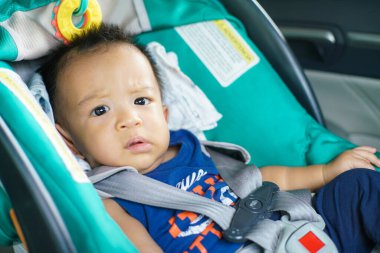 Çocuk emniyet koltuğundaki mutlu çocuk portresi. Arabada sabırla oturuyor. Arabada koruma.