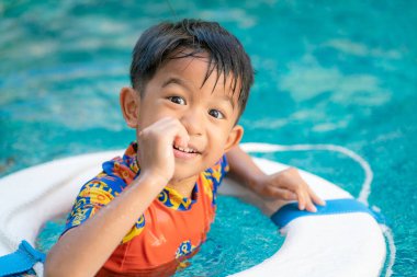 Mutlu Asyalı anaokulu çocuğu annesiyle açık hava aktivitelerinde yüzüyor.