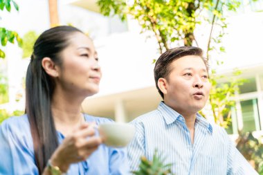 İş adamı ve kadın sabah kahvaltısı ile ev bahçesinde konuşuyorlar.