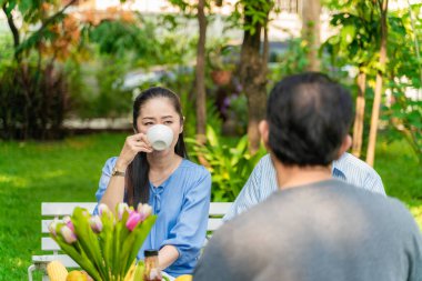 İş adamı ve kadın sabah kahvaltısı ile ev bahçesinde konuşuyorlar.