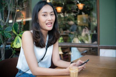 Asian women sitting in cafe drinkking hot latte coffee