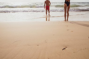Couple walking on sea beach into the sea summer beach