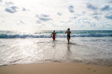 Couple walking on sea beach into the sea summer beach