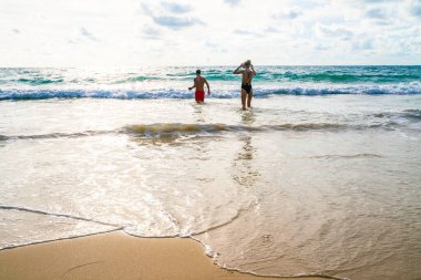 Couple walking on sea beach into the sea summer beach