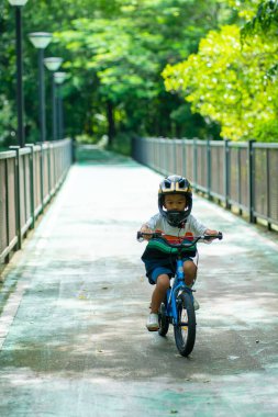 Küçük anaokulu çocuğu bisiklet parkında bisiklet sürme alıştırması yapıyor.