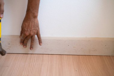 Mekanik adam, yeni evin içini kaplatıyor. Kahverengi ahşap zemin.