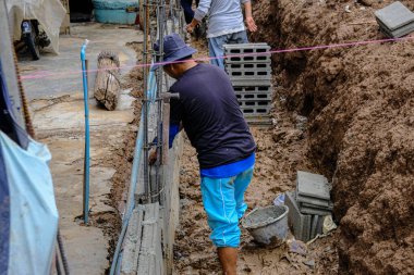 Metal anket alanı olan tuğla duvar inşaatında çalışan mekanik bir adam.