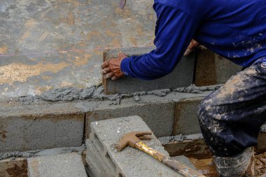 Metal anket alanı olan tuğla duvar inşaatında çalışan mekanik bir adam.