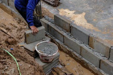 Metal anket alanı olan tuğla duvar inşaatında çalışan mekanik bir adam.