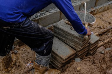 Metal anket alanı olan tuğla duvar inşaatında çalışan mekanik bir adam.