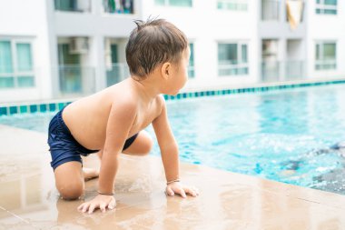 Apartman havuzunda küçük sevimli bir çocuk, açık hava aktivitesi.