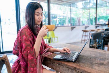 Kafede oturan iş kadını, kahve içiyor dizüstü bilgisayarla online konferans yapıyor.