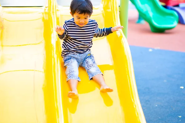 stock image Little asian boy playing in outdoor playground slider and crimbing happy boy