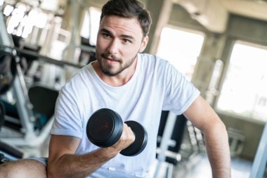 Jimnastik salonunda Dumnbell 'le egzersiz yapan yakışıklı bir sporcu. Sağlıklı Yaşam Tarzı