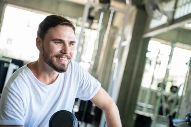 Jimnastik salonunda Dumnbell 'le egzersiz yapan yakışıklı bir sporcu. Sağlıklı Yaşam Tarzı