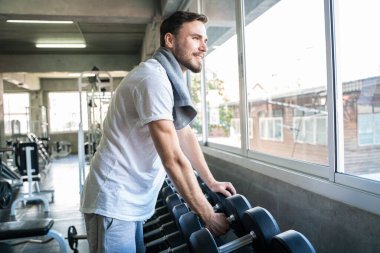 Jimnastik salonunda Dumnbell 'le egzersiz yapan yakışıklı bir sporcu. Sağlıklı Yaşam Tarzı