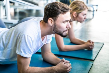 Akıllı adam ve kadın arkadaş şınav çekiyorlar ve kapalı alanda beden eğitimi egzersizi yapıyorlar.