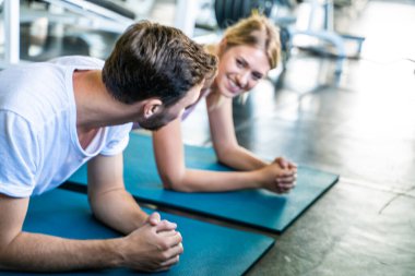 Akıllı adam ve kadın arkadaş şınav çekiyorlar ve kapalı alanda beden eğitimi egzersizi yapıyorlar.