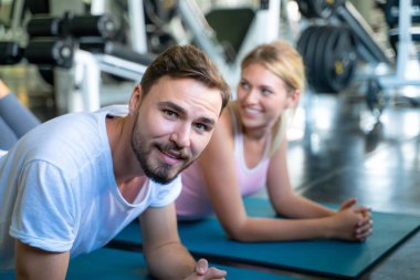 Akıllı adam ve kadın arkadaş şınav çekiyorlar ve kapalı alanda beden eğitimi egzersizi yapıyorlar.