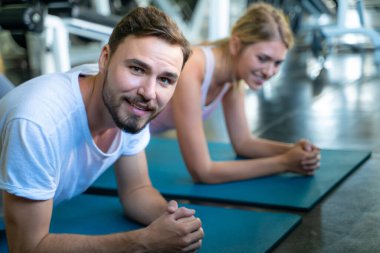Akıllı adam ve kadın arkadaş şınav çekiyorlar ve kapalı alanda beden eğitimi egzersizi yapıyorlar.