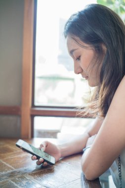 İş kadını Asyalı kadın kahve içerken akıllı telefon iletişimini kullanır. Güzel kadın.