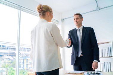 İş adamı ve kadın selamlaşarak selamlaşır, selamlar ya da teşekkürler jestleri yapar.