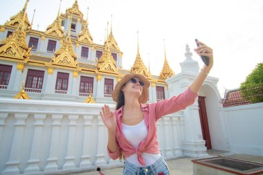 Sırt çantalı turist kadın, Bangkok Tayland 'da Buda Tapınağı' nı gezerken Samrtphone ile fotoğraf çekiyor.