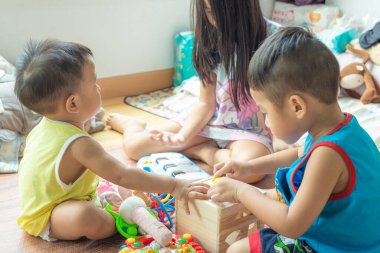 Mutlu anaokulu çocukları rahat evlerinde ahşap oyuncaklarla eğleniyorlar. Kardeşler birlikte oynuyorlar.