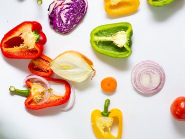 Beyaz arka planda çeşitli renkli sebze dilimleri sağlıklı yiyecekler.