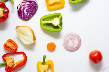 Beyaz arka planda çeşitli renkli sebze dilimleri sağlıklı yiyecekler.