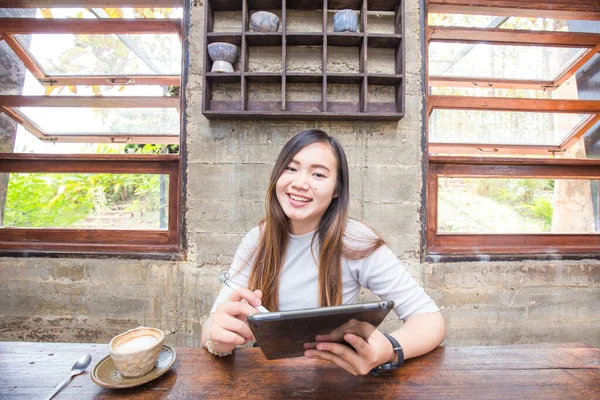 美しいアジアの女性はコーヒーショップ笑顔ビジネス女性でタブレットコンピュータを使用しています — ストック写真