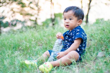 Mutlu Asyalı çocuk yeşil çimlerde oynuyor açık hava parkında gün batımı doğa