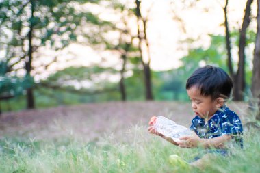 Mutlu Asyalı çocuk yeşil çimlerde oynuyor açık hava parkında gün batımı doğa
