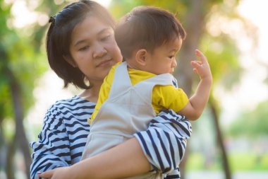 Anne kucağında bebekle gün batımında dinleniyor.