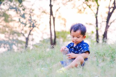 Mutlu Asyalı çocuk yeşil çimlerde oynuyor açık hava parkında gün batımı doğa